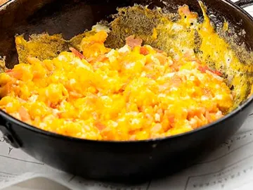 Huevos revueltos con jamón y tomate recién hechos en el sartén